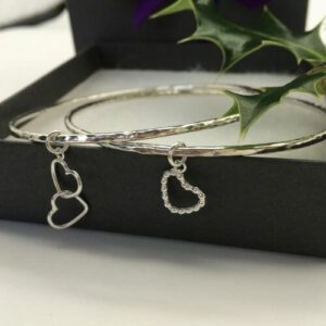 sterling silver stacking bangle. Hand plannished with hammer and option to add a single or interlocking heart charms