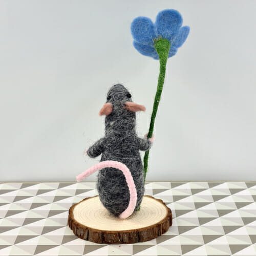 Back view of grey needle felted mouse with forget-me-not flower