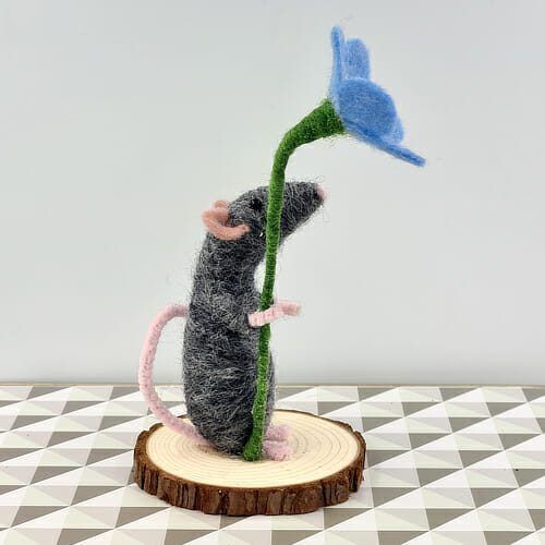 side view of grey needle felted mouse with forget-me-not flower