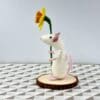 side view of needle felted white mouse holding a daffodil
