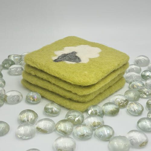 Stack of needle felted green coaster with white sheep