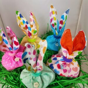 Multi coloured gift bags with bunny ears sit on green paper grass.