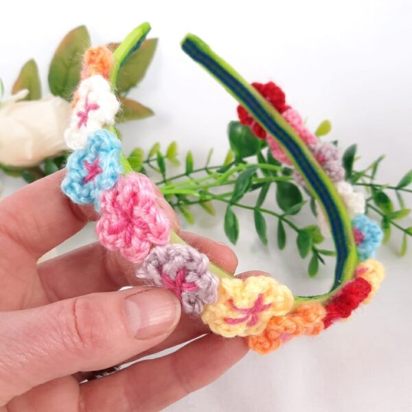Colourful small crochet flowers on a green headband.