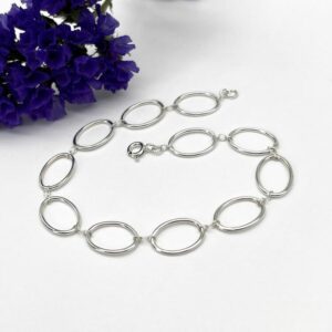 fine silver chain bracelet made of oval links connected by small round links, fastened with a bolt ring clasp.