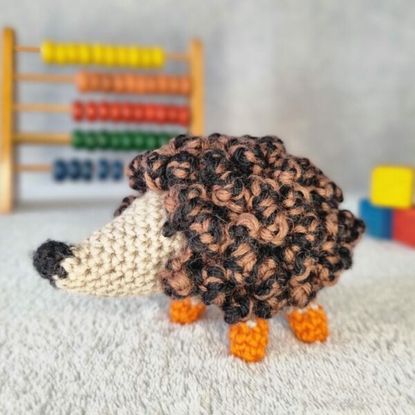 Handmade hedgehog made of wool with orange feet.