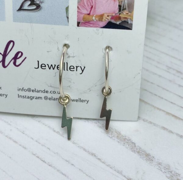 silver hoop earrings with a lightning strike charm on a business card