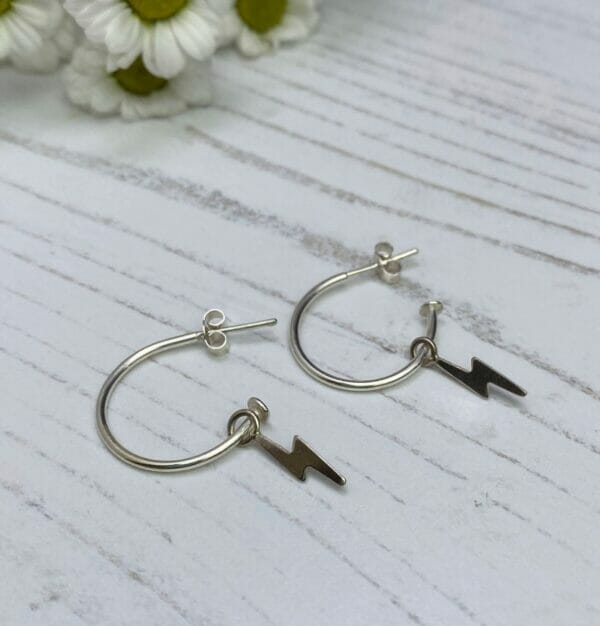 Silver hoop earrings with lightning charms shown on side