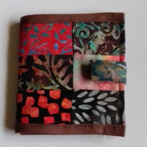 Patchwork card wallet in shades of orange, red, brown and green, closed fastened with tab
