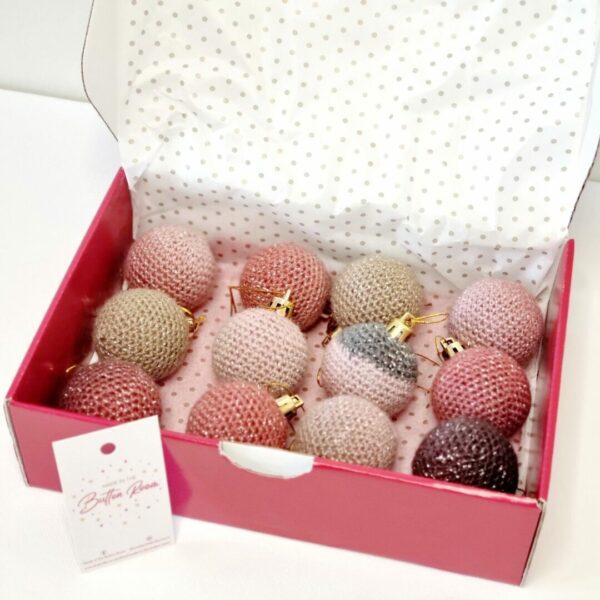 Box of blush coloured baubles in a red postage box with white background