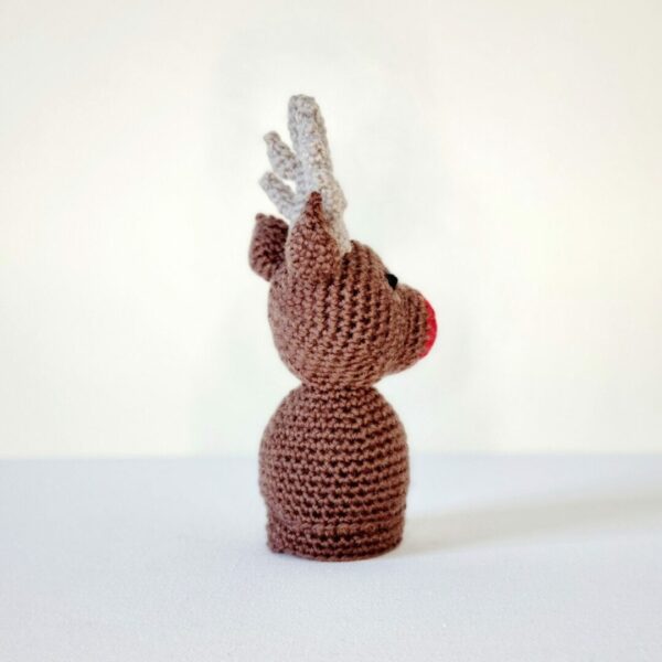 Side view of a brown crochet reindeer on a white background