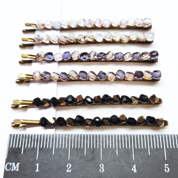 Set of six hair grips with crystal bead embellishments along the top edge. Clear, pink and purple, black and gold.