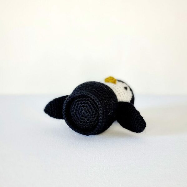 Bottom view of the base of a black and white crochet penguin on white background