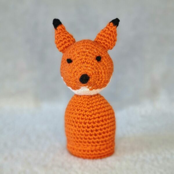 A single orange fox soft toy with white chin, black tip ears on a light grey background.