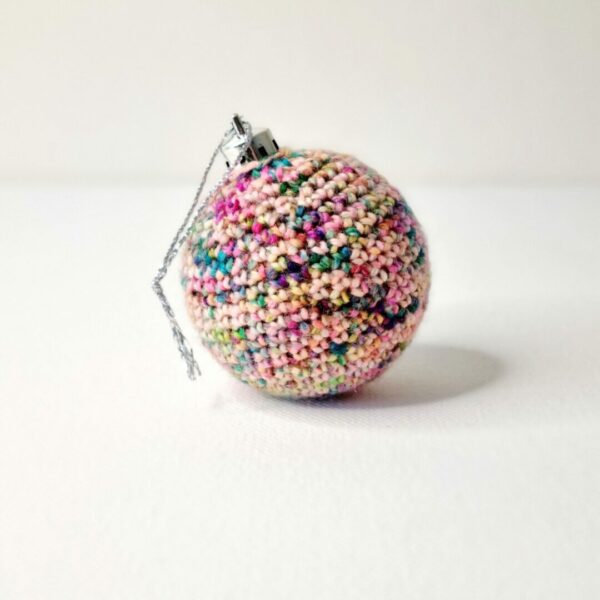 A single rainbow coloured crochet bauble on a white background