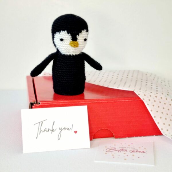 Black and white penguin sat on top of a red postage box along side a thank you card and gold polka dot paper.