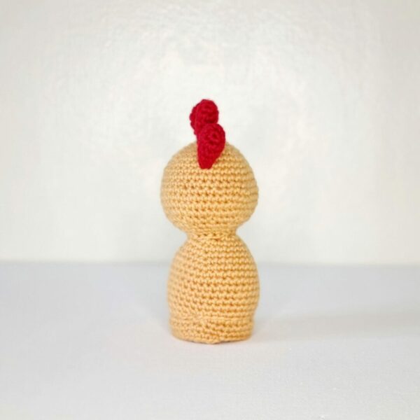 back view of yellow crochet chicken with a red comb