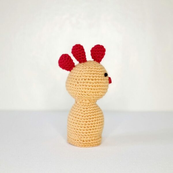 side angle of a small crochet yellow chicken with red comb and beak