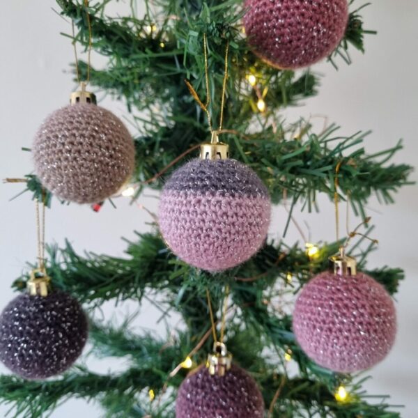 Mini crochet baubles in blush tones hanging from a Christmas tree