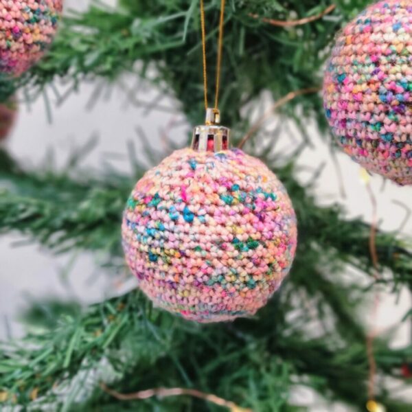 Close up image of a crochet bauble hanging from a Christmas tree