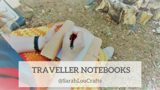 Photograph taken over the shoulder of a person sitting in a camping chair in front of a campfire, writing in a cork fabric notebook journal with white pages.