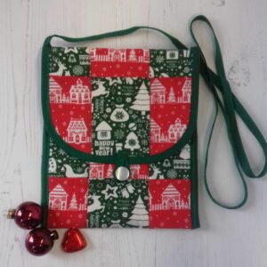 Small rectangular bag made from a patchwork of red and green festive cotton fabric squares, with narrow green strap and green trim
