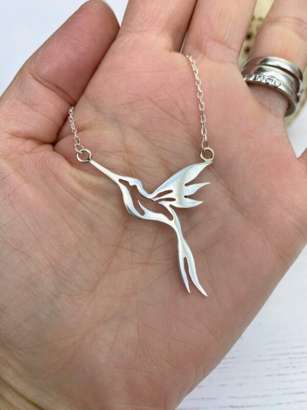 Silver hummingbird necklace on hand