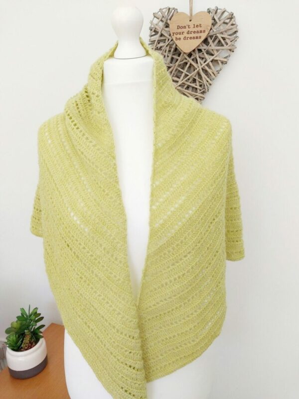 Crochet triangle shawl wrap in a soft sunflower yellow shown draped on white mannequin.