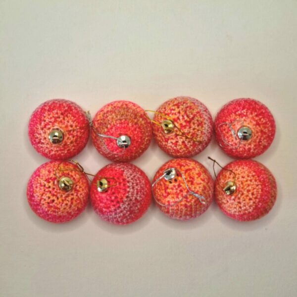 Red and peach coloured baubles lined up on a white background