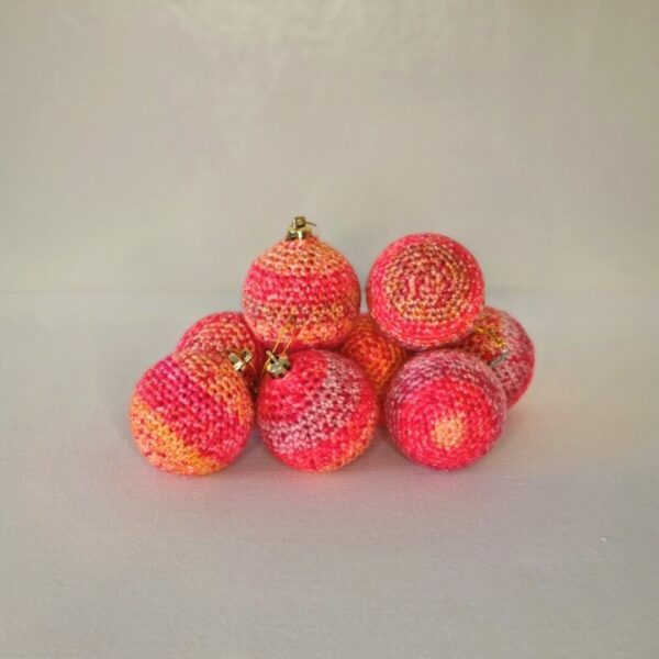 A small pile of red and peach striped baubles on a white background