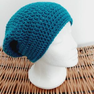 Crochet slouchy beanie hat in Ocean Sea Blue aran yarn, shown right side at an angle on a white mannequin head.