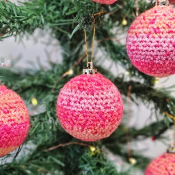 Pink Ombre crochet baubles hanging from a Christmas tree.