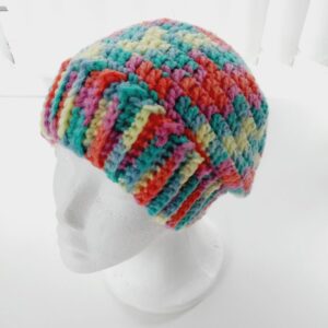 Multicoloured beanie hat with wide brim in rainbow yarn shown on white mannequin head.