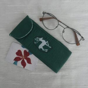 A dark green glasses case with an appliqued deer on the front, shown with a pair of spectacles