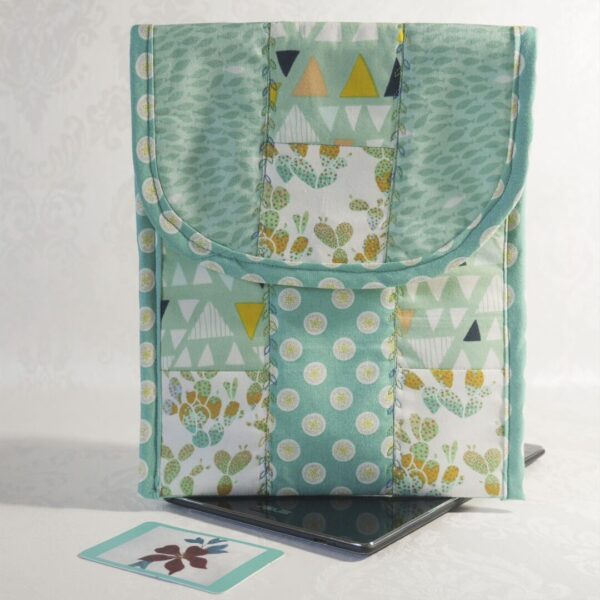 Patchwork tablet case in shades of green and gold cotton prints, some featuring cacti, shown with electronic tablet.