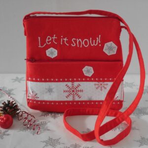 A compact red and white crossbody bag with front zipped pocket and zip closure on the top, appliqued snowflakes and stitched wording: Let it snow.