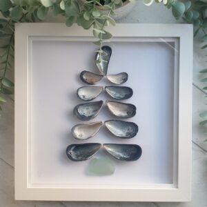 A tree made using upturned mussel shells shook that their pearly insides show. The stump is made from a piece of seaglass.
