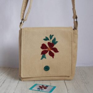 Light beige coloured bag with crossbody strap and appliqued red clematis flower on the front