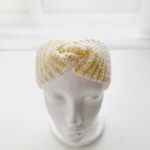 Crochet ear warmer headband with top twist in a soft lemon yellow and white colourway yarn. Shown on white mannequin head.