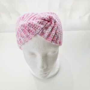 Crochet ear warmer headband with top twist in pink and white colourway yarn. Shown on white mannequin head.