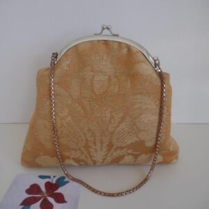 Frame clutch purse made from vintage damask fabric in shades of gold and orange, with chain strap