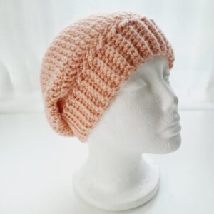 Pale blush pink crochet slouchy beanie hat with wide brim shown on a white mannequin head.