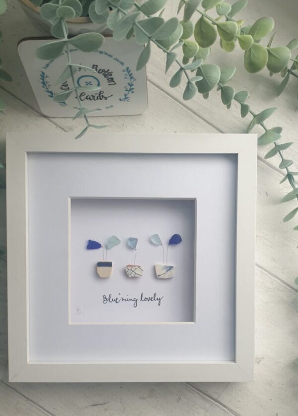 Framed and mounted picture of flower pots with blue and white sea pottery and different shades of blue seaglass.