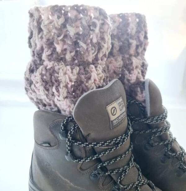 Crochet boot cuff ankle warmers, in a variegated yarn of brown, pink and cream shades. Shown in brown hiking boots.