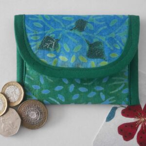 Envelope style purse made from batik printed fabric in shades of blue and green shown with coins and business card