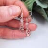 Dangly earrings with round jade gemstone beads and hand crafted silver swirl in a stylised curl shape.