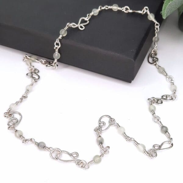 Sterling silver chain link necklace with handcrafted silver swirls, a clasp which blends seamlessly into the design and jade gemstone beads interspersed along the length of the chain.