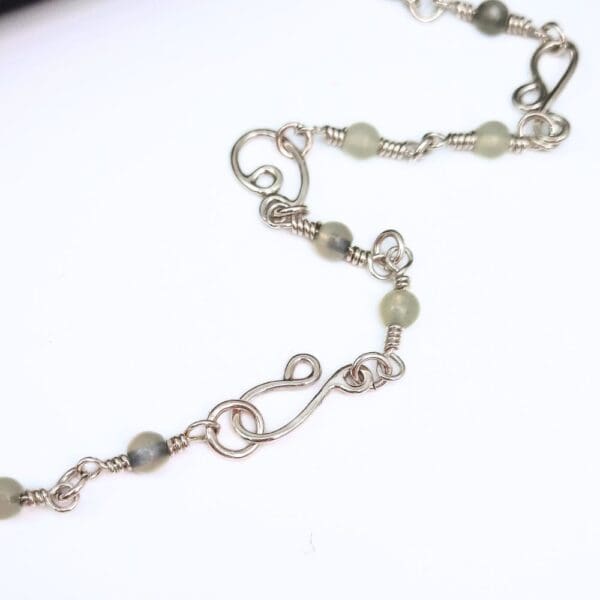 Sterling silver chain link necklace with handcrafted silver swirls, a clasp which blends seamlessly into the design and jade gemstone beads interspersed along the length of the chain.