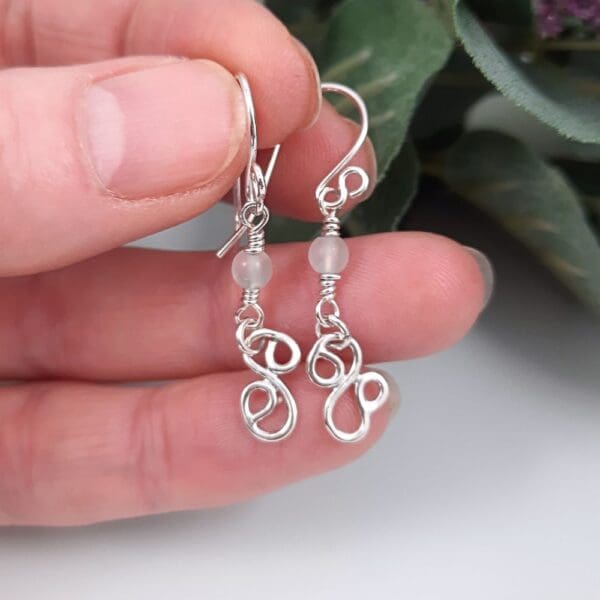 Dangly earrings with round jade gemstone beads and hand crafted silver swirl in a stylised S shape.