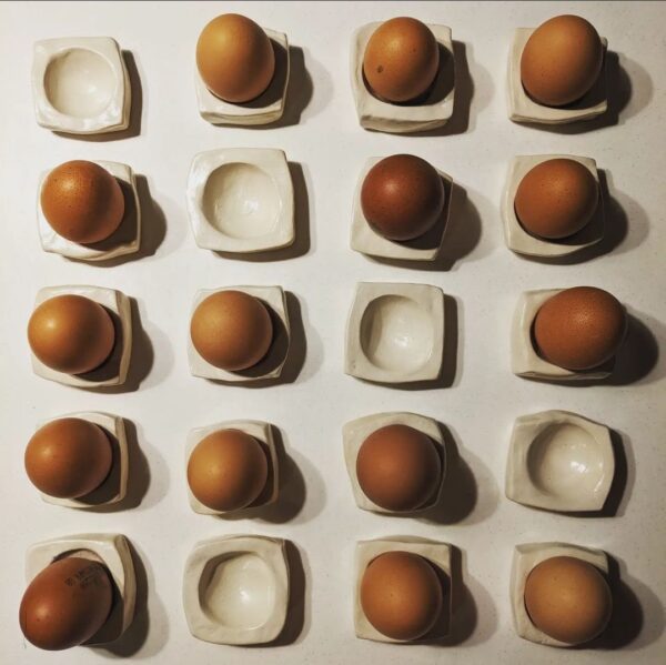Rows of hand moulded white egg cups with eggs sat inside them.