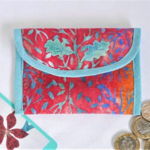 Envelope style coin purse, red printed cotton featuring blue leaves, trimmed in light blue. Shown with coins and a business card.